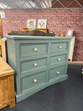 Load image into Gallery viewer, A charming pine chest of drawers featuring six spacious drawers in a sophisticated mid-green finish. Structurally sound with character marks, this piece combines practical storage with timeless style. An ideal statement focal point for any bedroom or living space, offering generous capacity without compromising on aesthetic appeal.
Delivery Available
Overall Dimensions
132cm wide x 48cm deep x 104cm high