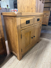 Load image into Gallery viewer, This Oak Furniture Land sideboard combines solid construction with practical storage. Featuring two dovetail-jointed drawers above a spacious double cupboard with internal shelf, it offers versatile display and concealment options. As a pre-loved piece, it bears the character marks of use, yet remains structurally sound and fully functional. Ideal for adding warmth and storage to any room with its classic oak appeal.
Delivery Available
Overall Dimensions
84cm wide x 35cm deep x 77.5cm high 