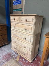 Load image into Gallery viewer, This tall stripped pine chest of drawers showcases beautiful natural wood grain, ready for your finishing touch. The piece features two short drawers positioned above four generous long drawers, offering ample storage for bedrooms or living spaces. Structurally sound and in good condition, it may benefit from a protective coat of wax to enhance and preserve the wood.
Delivery Available
Overall Dimensions
77cm wide x 40cm deep x 108cm high 