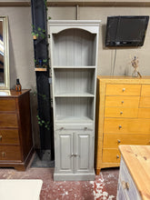 Load image into Gallery viewer, A charming narrow pine bookcase with authentic character. Finished in grey, it shows gentle patina and may benefit from minor touch-ups. Features two fixed shelves, a dovetail-jointed drawer, and a double cupboard—ideal for displaying books and storing essentials. Structurally sound and ready to enhance any room with classic appeal.
Delivery Available
Overall Dimensions
51cm wide x 24cm deep x 183cm high