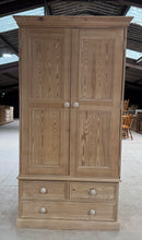 Load image into Gallery viewer, This solid pine wardrobe showcases beautiful natural wood grain, stripped back to reveal its authentic character. The piece features one hanging rail positioned above three dovetail-jointed drawers—two shallow and one deep—offering versatile storage for clothing and accessories. Structurally sound and in good condition, this wardrobe suits country, rustic, and traditional interiors beautifully. The natural finish may benefit from a protective coat of wax to enhance durability and appearance. Designed for pr