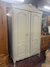 Load image into Gallery viewer, This stunning cream armoire features a beautifully subtle distressed finish that captures authentic shabby chic character. Structurally sound and in excellent condition, it offers two separate cupboards, each fitted with a hanging rail for versatile storage. The piece fully dismantles into panels, making transport and repositioning effortless. Perfect for adding vintage charm to any bedroom or dressing room. Comes complete with key.
Delivery Available
Overall Dimensions
120cm wide x 57cm deep x 201cm hig