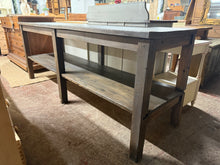 Load image into Gallery viewer, Transform your garden room or hallway with this robust wooden potting table that's ready for a new chapter. Solidly built and wonderfully functional, it features a spacious work surface ideal for potting plants or displaying treasured items, plus a handy lower shelf for keeping supplies within reach. The natural wear marks are badges of honour, reflecting years of reliable service. Whether you're a keen gardener or simply seeking a characterful storage solution, this versatile piece brings both practicality