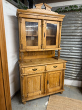 Load image into Gallery viewer, This charming antique pine dresser is sturdy and in great shape considering its age. It shows some typical wear from years of use, but nothing too noticeable. Being a vintage item, it has been treated for woodworm, so you can rest easy. The dresser includes one shelf in the upper section, two dovetailed drawers below, and a double cupboard. It also separates into two pieces to make moving simpler.
Overall Dimensions
115cm wide x 50cm deep x 216cm high
DELIVERY AVAILABLE      
For our other items see our