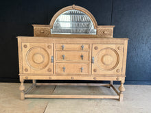 Load image into Gallery viewer, A striking stripped oak sideboard with authentic character and versatile appeal. This piece features three dovetail-jointed drawers and two single cupboards, offering substantial storage for any room. The removable mirror top adds flexibility for display or relocation. Returned to its natural wood finish, it may benefit from wax treatment to enhance protection and lustre. Structurally sound and in good condition, this is a statement piece that brings warmth and craftsmanship to contemporary or traditional i