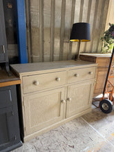 Load image into Gallery viewer, Made from oak and finished in Farrow & Ball's sophisticated London Stone, this pre-loved sideboard brings authentic character to any room. Two dovetail-jointed drawers sit above a spacious double cupboard—ideal for storing tableware, linens, or décor. Vintage patina and minor surface marks add to its charm. Structurally sound and ready to enhance country, transitional, or eclectic interiors.
Delivery Available
Overall Dimensions
123cm wide x 47cm deep x 88cm high