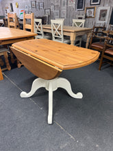 Load image into Gallery viewer, A charming solid pine drop leaf dining table that brings warmth and character to any dining space. Featuring cream-painted legs and a beautifully waxed antique pine top, this piece combines classic style with practical functionality. The sturdy construction ensures reliable everyday use, while the compact design with drop leaves makes it perfect for flexible entertaining. Comfortably accommodates four diners, ideal for intimate family meals or gatherings with friends.
Overall Dimensions
105cm diameter x 7