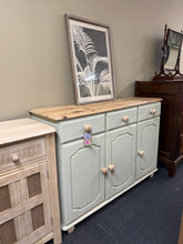 Load image into Gallery viewer, A striking sage green pine sideboard that combines practical storage with distinctive style. Features a two-tone design—natural wood top, handles, and feet contrast beautifully with the soft sage green painted body. Three short drawers sit above a double cupboard and single cupboard, offering flexible storage for dining rooms, hallways, or living spaces. Structurally sound and in good condition, this piece brings both character and functionality to your home.
Delivery Available
Overall Dimensions
123cm w
