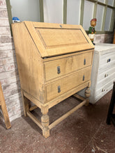 Load image into Gallery viewer, Authentic stripped oak bureau featuring a pull-down writing desk and two dovetail-jointed drawers. The natural wood finish showcases the grain character, though a protective wax coat is recommended to enhance durability. An elegant, functional piece for any home office or study.
Delivery Available
Overall Dimensions
73cm wide x 43cm deep x 101cm high 
