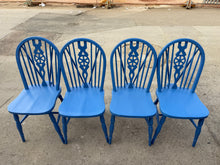 Load image into Gallery viewer, This charming set of four wheelback chairs brings character and warmth to any dining space. Each chair is structurally sound and in good overall condition, with the natural patina of well-loved vintage pieces. Minor surface marks add to their authentic appeal without compromising durability or comfort.
Perfect for those seeking to inject colour and personality into their dining area, these chairs work beautifully as a complete set or mixed with existing furniture for an eclectic look. Their timeless wheelba