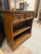 Load image into Gallery viewer, This beautiful oak bookcase is sturdy and generally in great shape. It shows some signs of use with minor marks, but nothing serious. It features two small drawers with dovetail joints and one shelf that can be removed.
Delivery Available
Overall Dimensions
75cm wide x 26cm deep x 81cm high