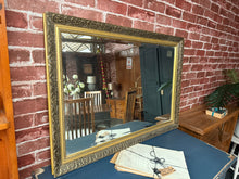 Load image into Gallery viewer, This beautiful gold bevelled edged mirror is solidly built and remains in great condition overall. It shows some signs of use, with minor marks that don’t detract from its charm. A hanging wire is attached to the back for easy display.
Delivery Available
Overall Dimensions
61cm x 87cm 