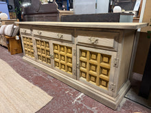 Load image into Gallery viewer, This substantial Younger Toledo sideboard has been stripped to bare wood, revealing its natural character. Structurally sound and in good overall condition, it would benefit from a protective wax finish. The top surface bears a mark that could be concealed with a darker stain if desired. Generous storage includes two short dovetail-jointed drawers, one long drawer, two single cupboards, and one double cupboard—ideal for keeping clutter at bay. A striking focal point for any interior, this piece combines pra