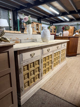 Load image into Gallery viewer, A striking Younger Toledo sideboard stripped to reveal its natural wood grain. This vintage piece showcases authentic craftsmanship with dovetail-jointed drawers and substantial storage across two short drawers, one long drawer, and three cupboards—perfect for living rooms or hallways.
The stripped finish highlights the wood's character, with minor surface patina that adds to its authentic appeal. A protective coat of wax is recommended to enhance durability and bring out the timber's warmth. An impressive