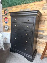Load image into Gallery viewer, A striking Willis & Gambier chest of drawers finished in classic black with period brass knobs. Features five spacious dovetail-jointed drawers plus a concealed top drawer, offering generous storage for any bedroom or hallway. The solid construction remains structurally sound, with light patina marks that add character to this vintage piece. An elegant addition to traditional or contemporary interiors.
Delivery Available
Overall Dimensions
90cm wide x 51.5cm deep x 133.5cm high 