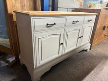 Load image into Gallery viewer, This beautiful pine sideboard is painted in 'Hessian' by Rustoleum, featuring an antique pine wax finish on the top. While the top shows a few minor marks, they don’t detract from its charm. It offers plenty of storage with three short dovetail-jointed drawers above three single cupboards, each adorned with a stylish black handle or knob.
Overall Dimensions
133.5cm wide x 46cm deep x 77cm high
DELIVERY AVAILABLE      
For our other items see our website https://fossewayfurniture.co.uk
collection from o