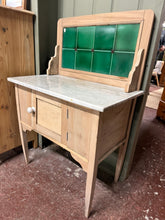 Load image into Gallery viewer, A charming late Victorian washstand featuring a removable marble top and decorative green tile splash-back. The piece has been stripped to reveal its natural wood finish, which can be enhanced with wax for added protection. Single cupboard provides practical storage. It has a slightly warped door which adds authentic character befitting its age. An elegant statement piece for period homes or vintage interiors.
Delivery Available
Overall Dimensions
76.5cm wide x 43cm deep x 114cm high 