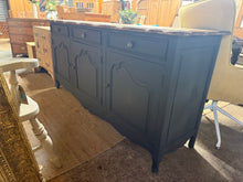 Load image into Gallery viewer, This elegant French-style sideboard brings timeless sophistication to any room. Freshly finished in Farrow and Ball's coveted off-black tone, it showcases a beautiful oak-waxed top that highlights the wood's natural character. Featuring practical storage with three generous drawers plus double and single cupboards, it's the perfect blend of style and function. A stunning statement piece that's ready to transform your space.
Overall Dimensions
187cm wide x 50.5cm deep x 88cm high
DELIVERY AVAILABLE