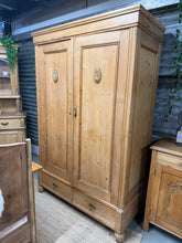 Load image into Gallery viewer, This characterful antique pine wardrobe combines practicality with period charm. Structurally sound and well-preserved, it bears the gentle patina of age—subtle marks and minor imperfections that enhance its authentic appeal. Inside, you'll find a full-length hanging rail for garments and two dovetail-jointed drawers offering generous storage. Designed with mobility in mind, the wardrobe completely dismantles for straightforward transport and repositioning. An ideal statement piece for period homes or anyon