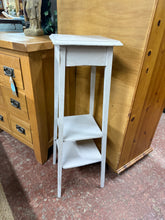 Load image into Gallery viewer, A charming wooden plant stand featuring a soft baby blue finish that shows character from previous use. The piece includes a practical lower shelf, ideal for storing plant accessories or displaying smaller items. While the paint could benefit from some refreshing in places, the stand remains structurally solid and in good working order.
Delivery Available
Overall Dimensions
25cm wide x 25cm deep x 83cm high - top measurement 