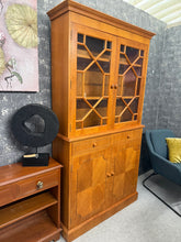 Load image into Gallery viewer, This elegant Georgian-style teak dresser combines timeless design with practical storage. Structurally sound and in good overall condition, it features two shelves in the upper section and one shelf in the lower cupboard—ideal for displaying treasures or storing essentials. Minor surface scratches and some veneer loss to the skirt are present but this does not compromise functionality. Designed to separate into two pieces for convenient transport and placement. A versatile addition to period or contemporary
