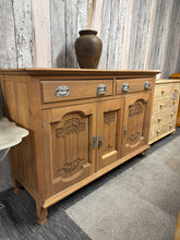 Load image into Gallery viewer, This beautiful satinwood sideboard has been stripped to reveal its natural grain and warm patina. Structurally sound with excellent joinery, it features two dovetail-jointed drawers above a double and single cupboard—ideal storage for dining rooms or hallways. The piece would benefit from a protective wax finish. Two handles require replacement and one foot has minor damage, both easily remedied. A rewarding project for those seeking authentic vintage character with solid bones.
Delivery Available
Overall