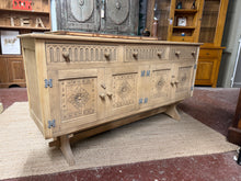 Load image into Gallery viewer, A substantial stripped oak sideboard crafted as a focal point for any dining or living space. The natural wood finish showcases authentic grain patterns and warm tones, though a protective wax coat is recommended to maintain its appearance over time. Practical storage includes three long drawers and two double cupboards, perfect for tableware, linens, or household essentials. The generous proportions and clean lines make this a versatile piece that complements both traditional and contemporary interiors.
D