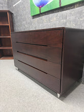 Load image into Gallery viewer, This modern brown chest of drawers combines practical storage with contemporary style. Featuring four spacious drawers, it offers ample room for bedroom essentials, linens, or living space organisation. Built to last, the piece is structurally sound and in good overall condition. As a pre-loved item, it bears gentle signs of use that add character without compromising functionality.
Delivery Available
Overall Dimensions
107cm wide x 46cm deep x 69cm high