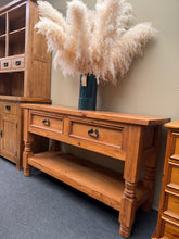Load image into Gallery viewer, This chunky pine hall table combines rustic charm with practical storage. Structurally sound and in good condition, it bears the character marks of used furniture. Two dovetail-jointed drawers provide secure storage for keys, post, and everyday essentials, whilst the lower shelf offers additional display or storage space. The solid construction and generous proportions make it an ideal focal point for hallways, entryways, or living spaces seeking both function and period appeal.
Delivery Available
Overall
