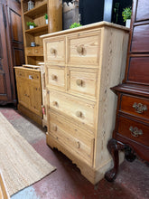 Load image into Gallery viewer, A striking tall chest of drawers crafted from solid pine and stripped back to reveal its natural grain and character. The piece features six generously proportioned drawers—four shorter compartments and two longer ones—all constructed with traditional dovetail joinery for durability and authentic craftsmanship. In its bare wood state, it offers a blank canvas for your finishing preferences, whether left natural for a rustic aesthetic or finished with wax or paint to suit your décor. Ideal for bedrooms, hall