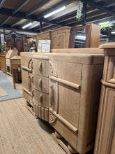 Load image into Gallery viewer, This striking Art Deco oak sideboard showcases authentic craftsmanship with dovetail joints. Stripped to bare wood, it reveals the natural grain and character of quality oak—perfect for those who appreciate vintage pieces. Features three dovetail-jointed drawers and two single cupboards offering generous storage. The unfinished surface allows you to personalise the finish with wax or oil to suit your space and desired patina. A timeless investment piece that brings period elegance to any room.
Delivery Ava
