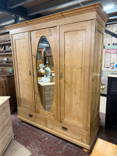 Load image into Gallery viewer, This stunning triple antique pine wardrobe is structurally sound and in good condition for its age. As a used piece, it bears authentic patina and minor marks that add character. It offers generous storage with one double cupboard featuring a hanging rail and shelf, one single cupboard with three shelves, and two dovetail-jointed drawers at the base. Comes complete with three keys. Please note: one door hinge is missing and can be easily replaced. The wardrobe dismantles for convenient transportation and re