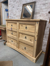 Load image into Gallery viewer, A spacious pine chest of drawers with a stripped finish, revealing the natural grain and character of the wood. Six generous drawers provide ample storage for bedroom essentials, clothing, and linens. The bare wood invites personalisation — consider applying wax or oil to enhance protection and achieve your desired aesthetic. Versatile enough for bedrooms, living spaces, or hallways. A timeless piece that celebrates natural wood beauty.
Delivery Available
Overall Dimensions
132cm wide x 48cm deep x 104cm
