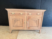Load image into Gallery viewer, This beautiful satinwood sideboard has been stripped back to reveal its natural wood grain, offering an authentic vintage character. While it may benefit from a protective wax finish, the piece retains excellent structural integrity despite minor surface marks and a small crack to one side that doesn't affect functionality. Featuring two dovetail-jointed drawers above a spacious double cupboard, it provides generous storage for dining rooms, hallways, or living spaces. A genuine piece with genuine patina.
