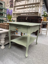 Load image into Gallery viewer, A charming side table finished in Boringdon green with subtle distressed detailing. This sturdy piece features a dovetail jointed drawer and lower shelf — perfect for storing books, blankets, or decorative items beside a sofa or bed. Structurally sound and ready to complement any room with vintage character and practical storage.
Delivery Available
Overall Dimensions
51cm wide x 67cm deep x 57cm high