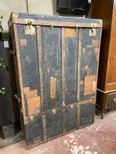Load image into Gallery viewer, This unique very old black metal travelling case is larger than most as it could be used as a wardrobe. It is structurally sound but could do with some TLC to make it new again. One of the handles on the side is broken but doesn't affect use. The top lifts up and the front can come out. The red velvet needs reattaching to the inside of the door. It has 'H.B Brevettes' engraved on the lock.
Overall Dimensions
103cm wide x 52.5cm deep x 149cm high 
DELIVERY AVAILABLE    
For our other items see our websit