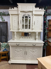 Load image into Gallery viewer, This glorious large French stye buffet is structurally sound and in good condition for its age. Unfortunately it does have a few knocks and bumps but that's to be expected of its age. It does come apart into 3 sections for easier moving. It offers ample storage with 2 shelves in the top section and 2 drawers over a double cupboard in the base. Previously painted in Creme de la Creme by Frenchic so could do with a touch up in places.
Overall Dimensions
approx : 150cm wide x 54cm deep x 246cm high 
DELIVER