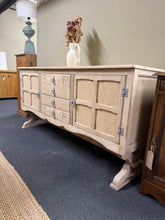 Load image into Gallery viewer, A beautiful stripped oak sideboard revealing the wood's natural grain and character. This piece features four dovetail-jointed drawers offering secure storage, plus two single cupboards with an internal shelf—ideal for displaying or concealing items. Structurally sound and in good condition, the bare wood finish allows you to personalise it with your choice of wax, oil, or stain.&nbsp;

Delivery Available

Overall Dimensions

164.5cm wide x 48.5cm deep x 81.5cm high

