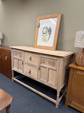 Load image into Gallery viewer, This striking stripped oak sideboard showcases authentic wood grain in its natural finish. Structurally sound and ready to live in your home, it features two cupboards—each with an internal shelf—and two dovetail-jointed drawers for timeless storage. The bare wood may benefit from a protective wax coat to enhance durability and depth. A versatile statement piece for any interior.

Delivery Available

Overall Dimensions

137cm wide x 47cm deep x 91.5cm high

