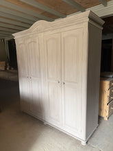 Load image into Gallery viewer, A spacious light grey pine wardrobe offering practical storage for any bedroom. This four-section piece features two double cupboards, each fitted with hanging rails for organised clothing storage. Structurally sound and in good overall condition, it shows minor surface marks that could be refreshed with a repaint if desired. Delivered fully dismantled for convenient transport and installation.

Delivery Available

Overall Dimensions

191cm wide x 62cm deep x 206cm high&nbsp;


