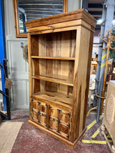 Load image into Gallery viewer, Mango wood bookcase in good working condition. Features two fixed shelves and a spacious double cupboard ideal for concealed storage. The piece shows minor cosmetic marks consistent with age and use, including a small aperture in the cupboard for cable management. Previous owners added lights which have'nt been tested but can be removed. A versatile storage solution with authentic character.

Delivery Available

Overall Dimensions

100cm wide x 51cm deep x 180.5cm high

