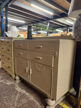 Load image into Gallery viewer, An elegant Art Deco sideboard, finished in Farrow &amp; Ball's sophisticated London Stone paint. Features four dovetail-jointed drawers providing generous storage above a double cupboard with internal shelf. The piece shows minor wear to the top surface consistent with its use, yet remains structurally sound and in good overall condition. A timeless addition to any home with classic proportions and quality joinery.

Delivery Available

Overall Dimensions

119cm wide x 46cm deep x 97cm + 8cm high

