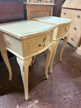 Load image into Gallery viewer, A matching pair of cream bedside tables featuring classic ornate detailing. Both units are in solid working order with minor cosmetic wear consistent with age and use. Each cabinet includes a single drawer for storage and sits beneath a practical removable glass top, making cleaning and maintenance straightforward. Ideal for adding vintage charm to a bedroom while maintaining everyday functionality.

Delivery Available

Overall Dimensions

36cm wide x 35cm deep x 63cm high
