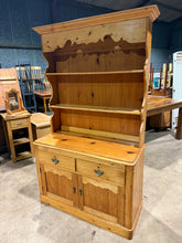 Load image into Gallery viewer, A characterful vintage pine dresser that combines practicality with period charm. Structurally solid and well-maintained, this piece showcases the natural patina of age with only minor surface marks. The design maximises storage across multiple sections: shelving in the upper portion, two dovetail-jointed drawers for secure storage, and a lower double cupboard. Thoughtfully constructed in two parts for convenient transport and placement. Ideal for those seeking authentic vintage furniture with genuine chara
