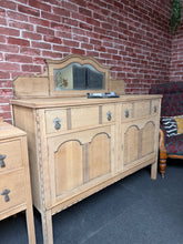 Load image into Gallery viewer, A striking stripped oak sideboard with authentic vintage character. Featuring solid dovetail jointed drawers and two cupboards for generous storage, this piece combines function with timeless style.&nbsp;The natural finish showcases the wood's grain and patina—it may benefit from a protective coat of wax. The removable mirrored plinth adds versatility; display it as shown or detach for a cleaner profile. Please note the mirror has some age-related clouding, adding to its period charm. A bold statement for a
