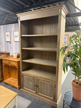 Load image into Gallery viewer, A charming limed wooden bookcase combining classic style with practical storage. Three fixed shelves provide ample display and storage space, while the lower double cupboard keeps items neatly concealed. Structurally sound with only minor cosmetic marks that add to its character. Perfect for living rooms, studies, or bedrooms seeking timeless appeal and functional organisation.

Delivery Available

Overall Dimensions

108cm wide x 39cm deep x 198cm high

