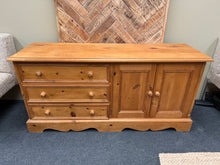Load image into Gallery viewer, A charming low pine sideboard with authentic character. Solidly constructed from solid pine with three spacious dovetail-jointed drawers and a double cupboard featuring an internal shelf. The piece shows gentle signs of age and use, adding to its vintage appeal. Ideal as a TV unit or versatile storage solution for any room. Structurally sound and ready to enhance your home.

Delivery Available

Overall Dimensions

133cm wide x 41cm deep x 64cm high

