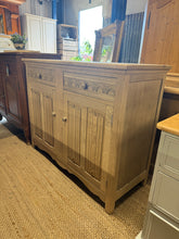 Load image into Gallery viewer, Maximize your storage space with our structurally sound Stripped Oak Sideboard. Its timeless beauty has been preserved and highlighted by a natural finish. It has ample storage with two drawers and a spacious double cupboard.

Overall Dimensions

115cm wide x 45cm deep x 89.5cm high

DELIVERY AVAILABLE      

For our other items see our website https://fossewayfurniture.co.uk

collection from our shop at cv36, our collection zone at bs36 or otherwise delivery is available

