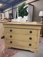 Load image into Gallery viewer, This elegant French cream chest of drawers combines timeless style with practical storage. Featuring three spacious dovetail-jointed drawers plus a concealed top drawer, it offers versatile organisation for any bedroom or hallway. Structurally sound with minor patina marks that add character, this piece is ideal for those seeking vintage charm with enduring quality.

Delivery Available

Overall Dimensions

118cm wide x 55.5cm deep x 83.5cm high&nbsp;

