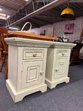 Load image into Gallery viewer, A charming pair of cream distressed bedside tables with authentic vintage character. Both pieces are structurally sound and ready to use. Each features one dovetail-jointed drawer over a cupboard, offering practical storage for your bedroom. One table has green on top—easily refreshed with cream paint if preferred. Perfect for adding warmth and character to a traditional or farmhouse-style bedroom.

Delivery Available

Overall Dimensions

48cm wide x 41cm deep x 67cm high

